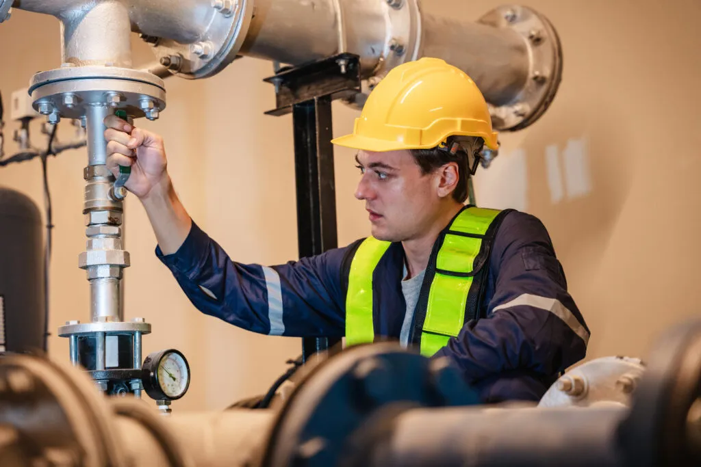A team of engineers is examining the plumbing and water valves inside an industrial facility